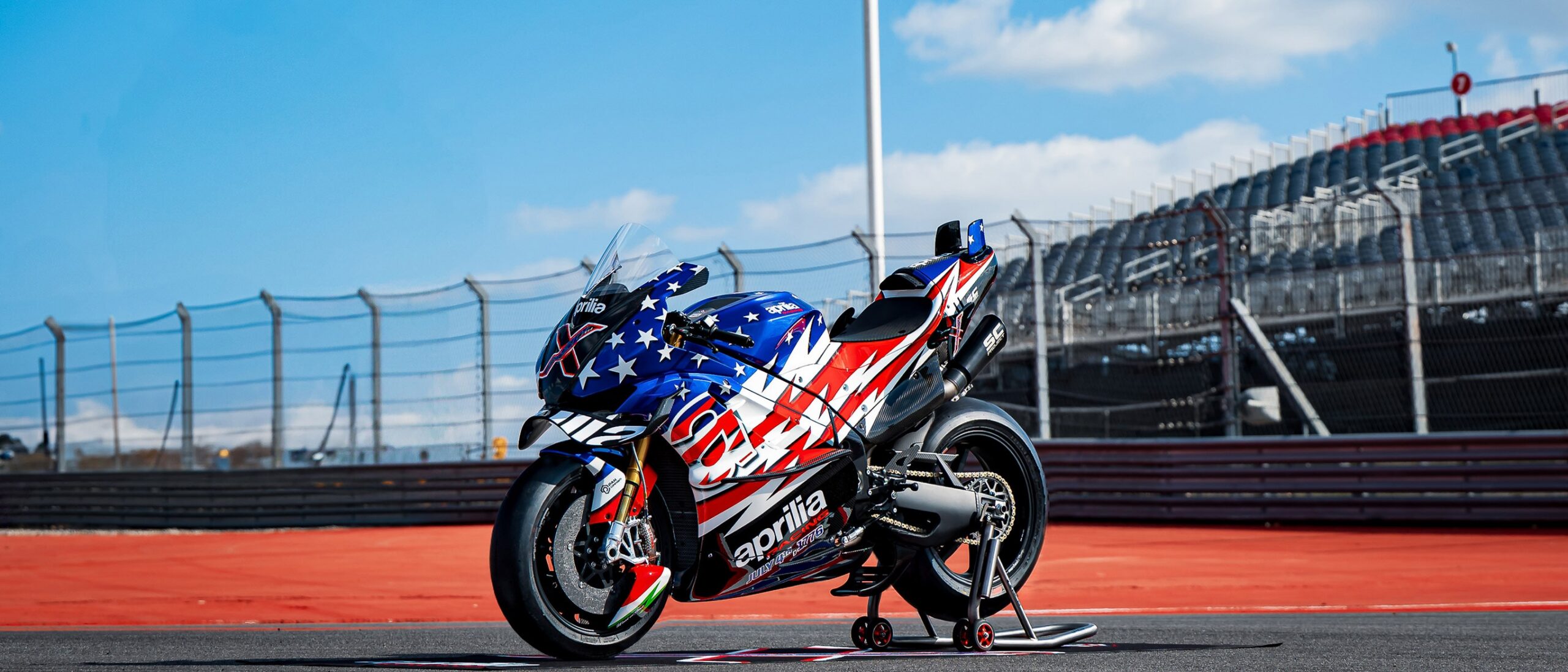 Profil boczny limitowanego motocykla Aprilia X 250TH z karbonowymi owiewkami, dużymi skrzydłami aerodynamicznymi i wyścigowym układem wydechowym na torze wyścigowym.