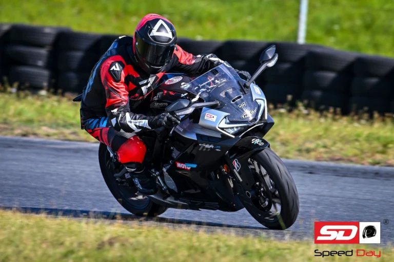 Protest motocyklistów przeciwko zamykaniu torów wyścigowych w Polsce, widoczny pusty tor Poznań z flagami sportowymi.