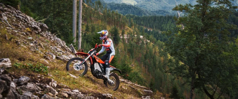 Nowy elektryczny motocykl KTM Freeride E 2027 w akcji na leśnej ścieżce, prezentujący lekką konstrukcję i terenowe opony.