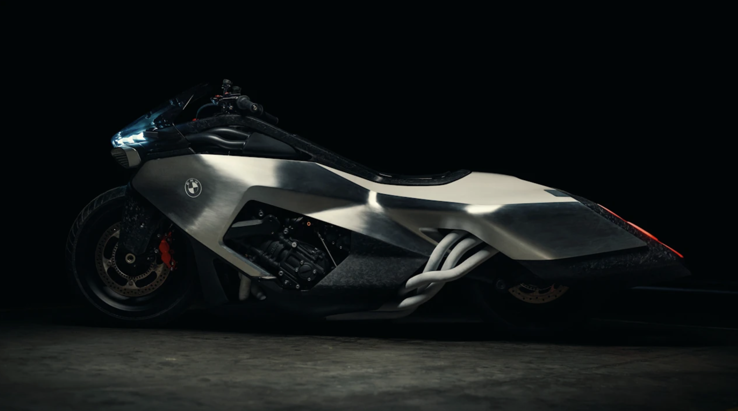 Futurystyczny prototyp motocykla BMW Vision K18 zaprezentowany nad jeziorem Como, eksponujący sześć rur wydechowych i kuty karbon.